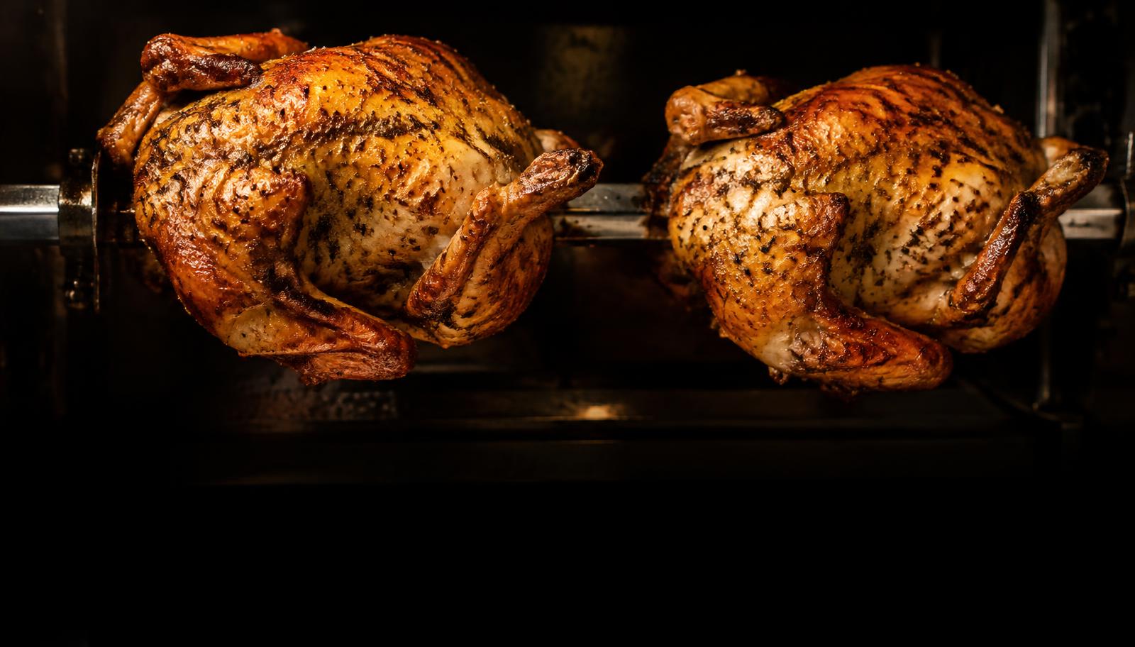 Herb-seasoned rotisserie chicken roasting over an open flame